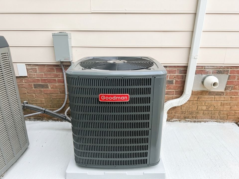 New Goodman AC condenser on a fresh pad at the side of the house