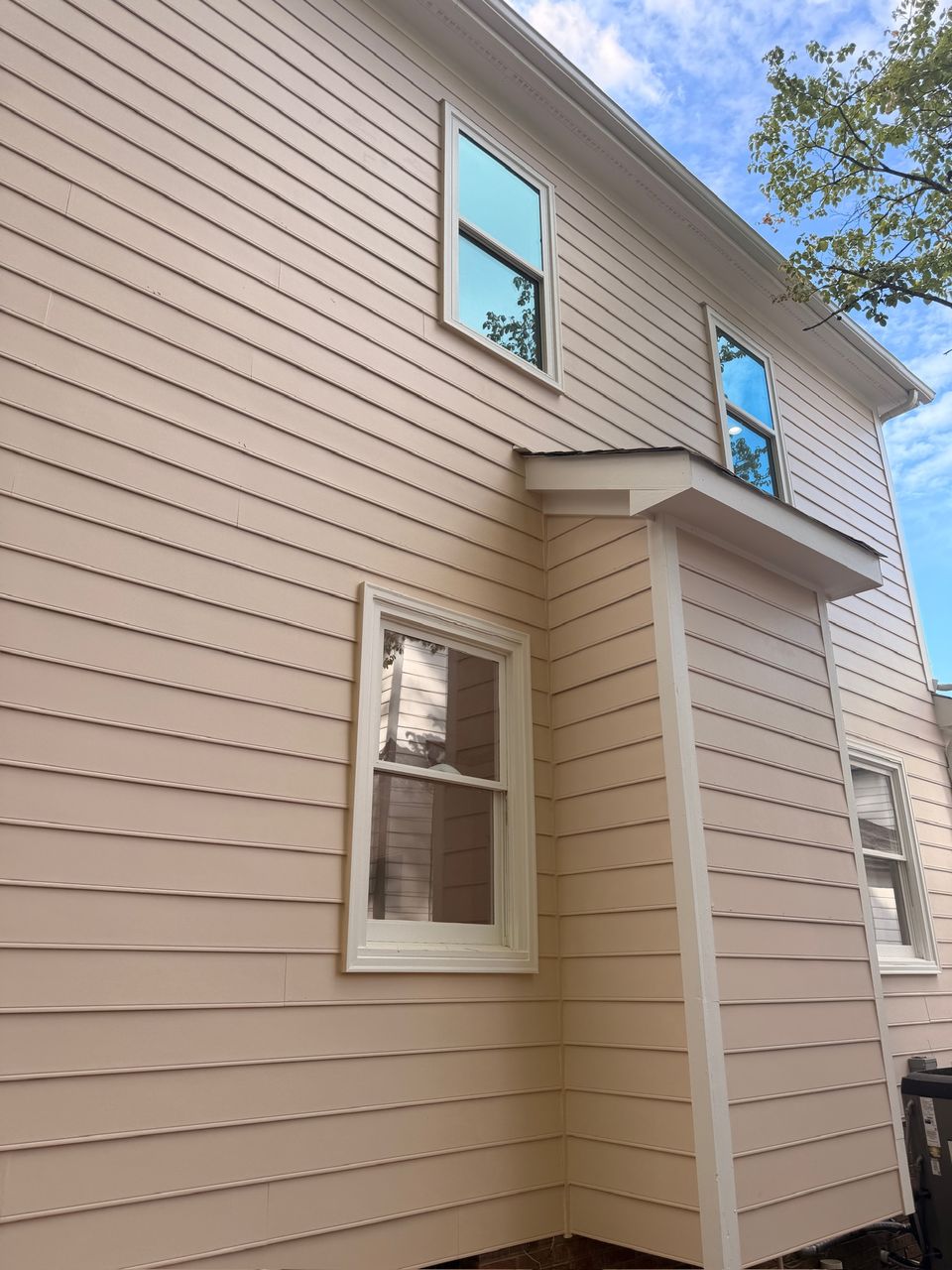 Tan lap siding and white window trim on the side of the house, finished